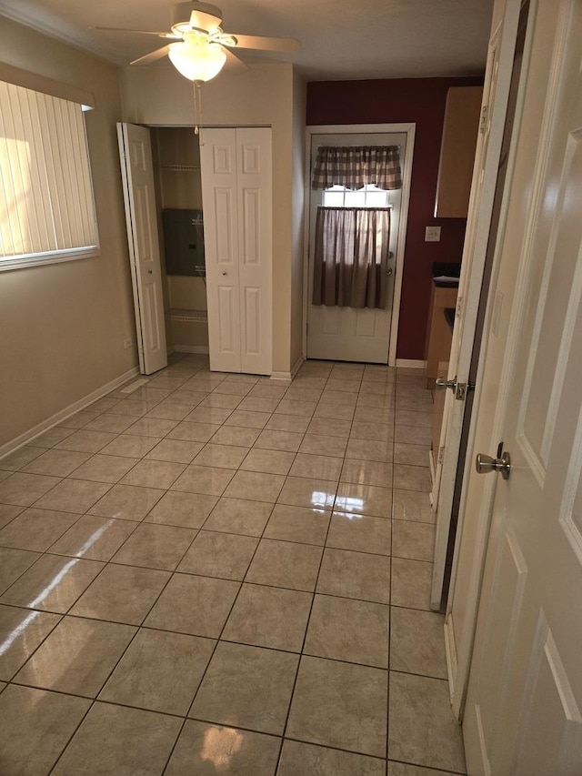 interior space featuring light tile patterned floors, ceiling fan, and baseboards