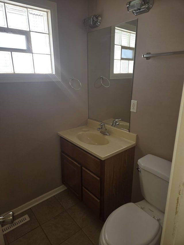 half bath with toilet, visible vents, tile patterned flooring, and vanity