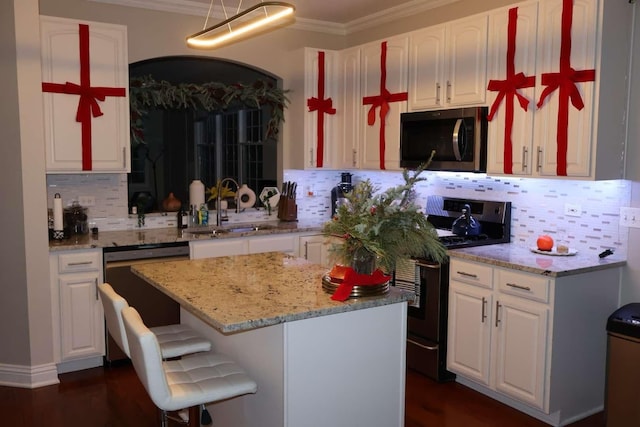 kitchen featuring appliances with stainless steel finishes, white cabinets, a sink, and ornamental molding