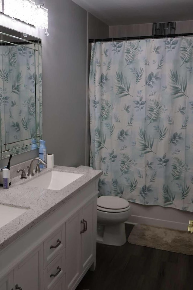 bathroom featuring toilet, shower / tub combo, wood finished floors, and vanity