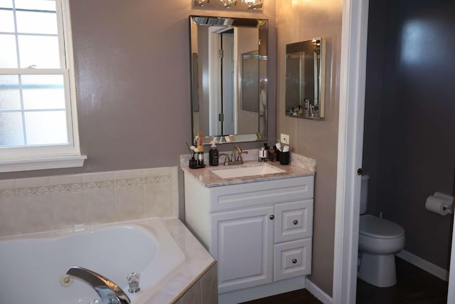 bathroom with a garden tub, vanity, and toilet