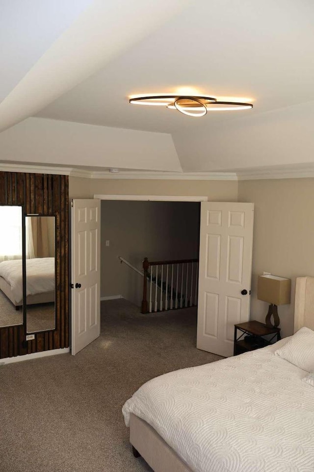 carpeted bedroom featuring lofted ceiling and ornamental molding