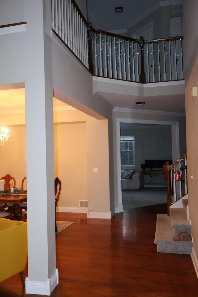 staircase featuring a towering ceiling, baseboards, and wood finished floors