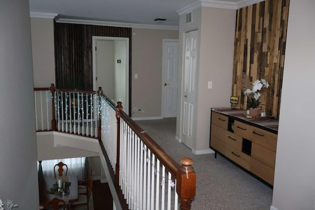 hallway with ornamental molding, carpet, baseboards, and an upstairs landing