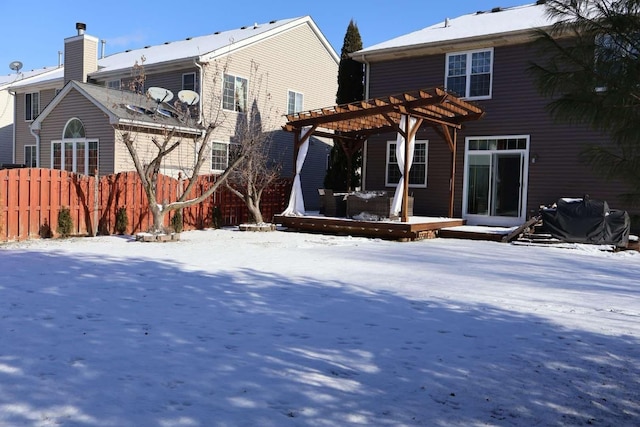 snow covered rear of property with fence, a deck, and a pergola