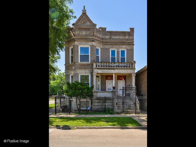 view of front of house featuring a balcony, a fenced front yard, and brick siding