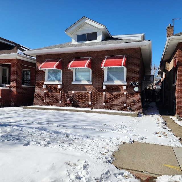 bungalow featuring brick siding