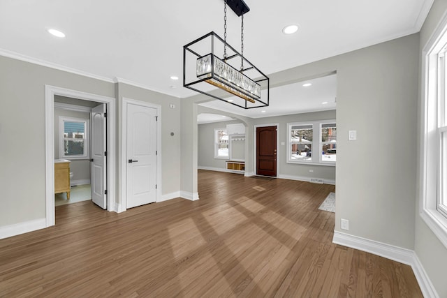 interior space with arched walkways, recessed lighting, ornamental molding, wood finished floors, and baseboards