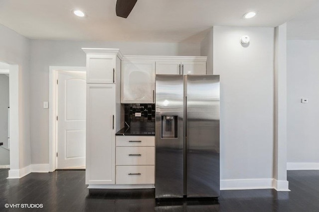 kitchen with dark wood-style flooring, white cabinets, backsplash, dark countertops, and stainless steel fridge