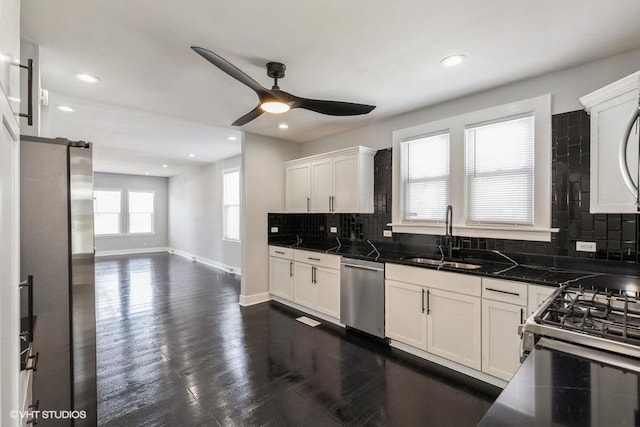 kitchen with baseboards, dark wood finished floors, white cabinets, appliances with stainless steel finishes, and a sink