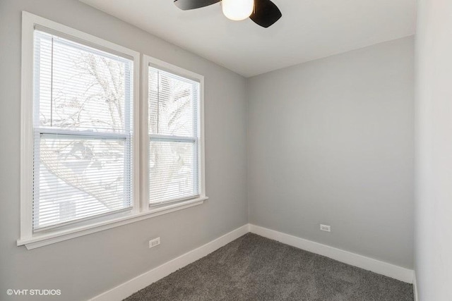 unfurnished room featuring dark carpet, plenty of natural light, a ceiling fan, and baseboards