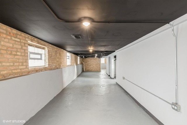 hall featuring brick wall, visible vents, and finished concrete floors