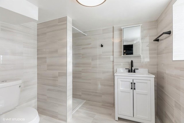 bathroom with toilet, a walk in shower, tile walls, and vanity