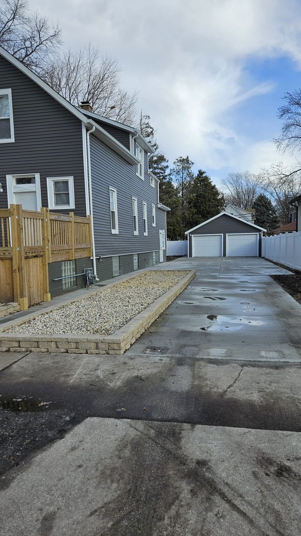 view of home's exterior with an outdoor structure, fence, and a detached garage