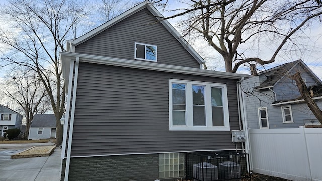 view of side of home with fence and cooling unit