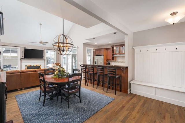 dining area featuring vaulted ceiling, a fireplace, dark wood finished floors, and recessed lighting