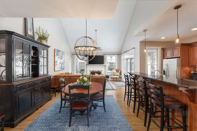 dining area with lofted ceiling, a chandelier, recessed lighting, a fireplace, and light wood-style floors