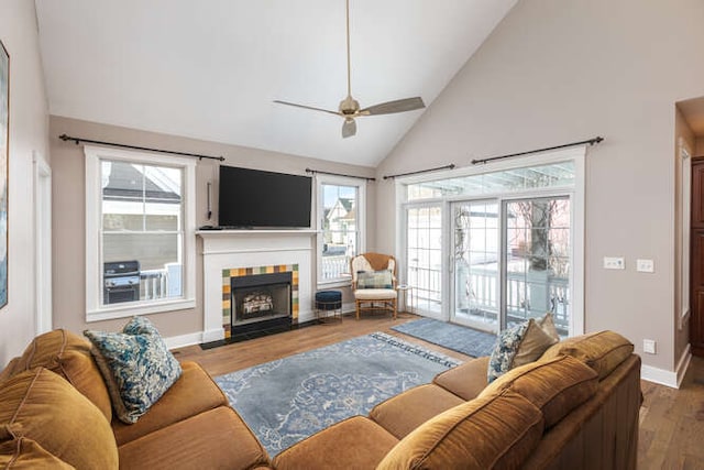 living room with baseboards, a healthy amount of sunlight, a tiled fireplace, and wood finished floors