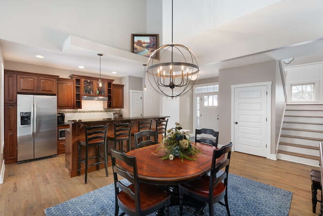 dining area featuring light wood finished floors, stairway, recessed lighting, and a notable chandelier