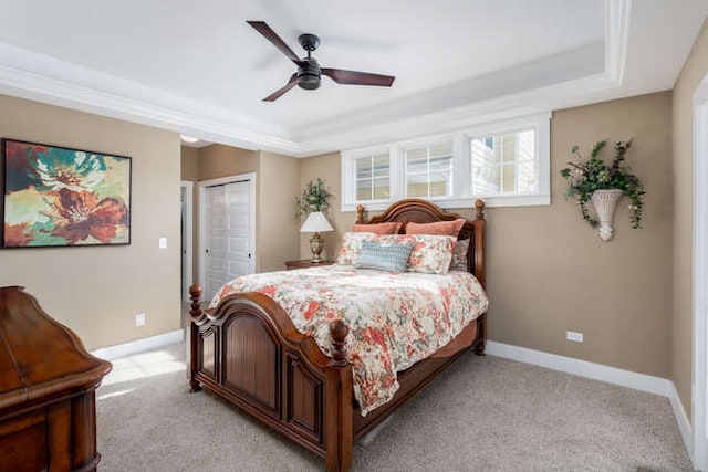 bedroom with baseboards, ceiling fan, a tray ceiling, and light colored carpet