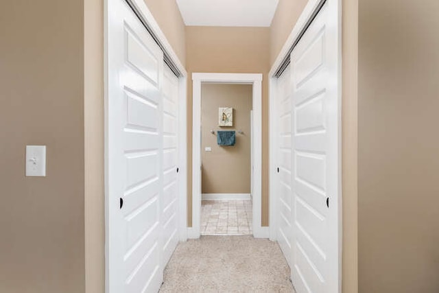 hall with light colored carpet and baseboards