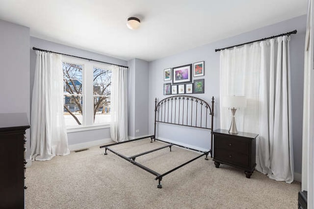 bedroom with baseboards and light colored carpet