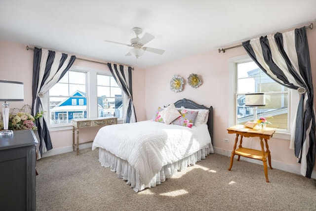 bedroom featuring multiple windows, light colored carpet, and baseboards