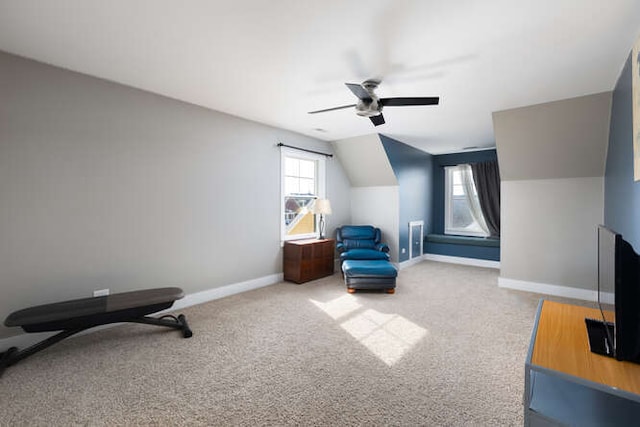 living area featuring lofted ceiling, carpet, baseboards, and a ceiling fan