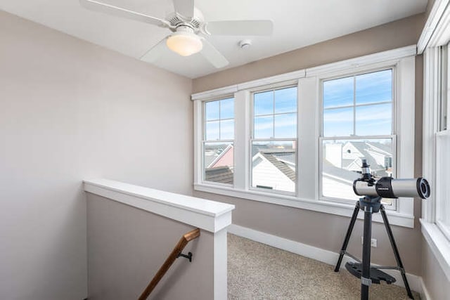 workout area with light colored carpet, ceiling fan, and baseboards