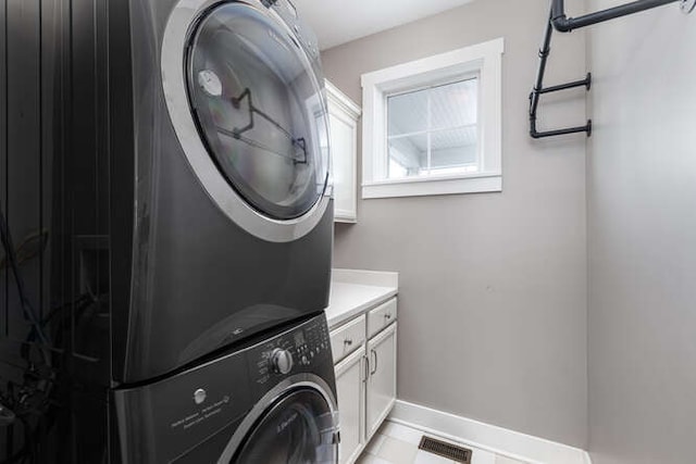 laundry room with visible vents, stacked washer and dryer, cabinet space, and baseboards