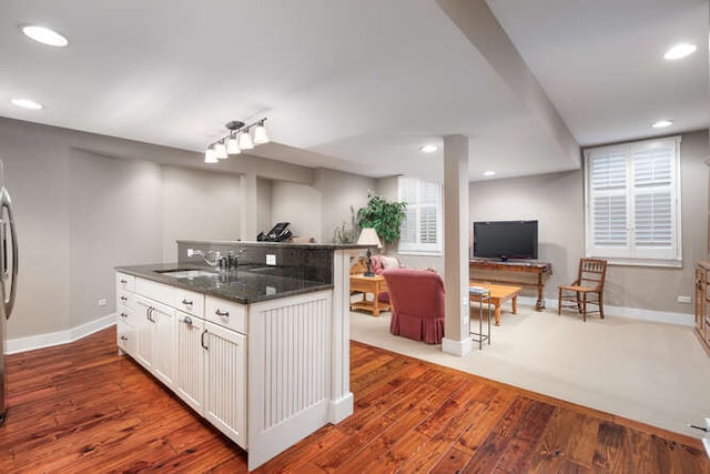 kitchen with open floor plan, dark wood-style flooring, a sink, and white cabinetry