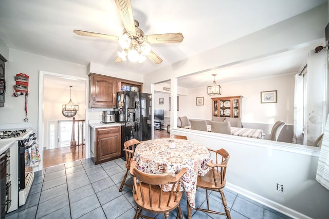 kitchen featuring black fridge with ice dispenser, gas stove, tile patterned floors, light countertops, and ceiling fan with notable chandelier