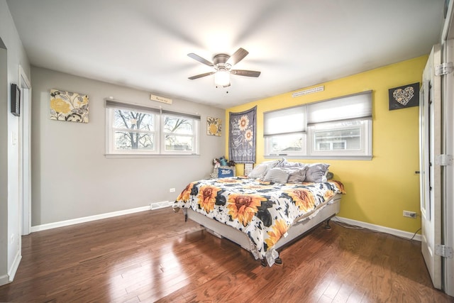 bedroom with a ceiling fan, baseboards, visible vents, and wood finished floors