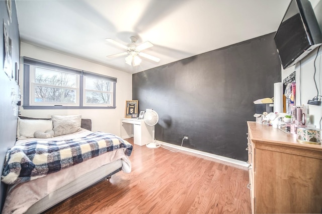 bedroom with light wood-type flooring, baseboards, and a ceiling fan