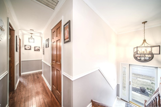 corridor with hardwood / wood-style floors, baseboards, a chandelier, and crown molding