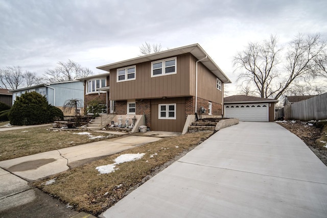 tri-level home featuring a garage, brick siding, an outdoor structure, and fence