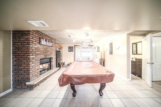 playroom with baseboards, light tile patterned flooring, visible vents, and a brick fireplace