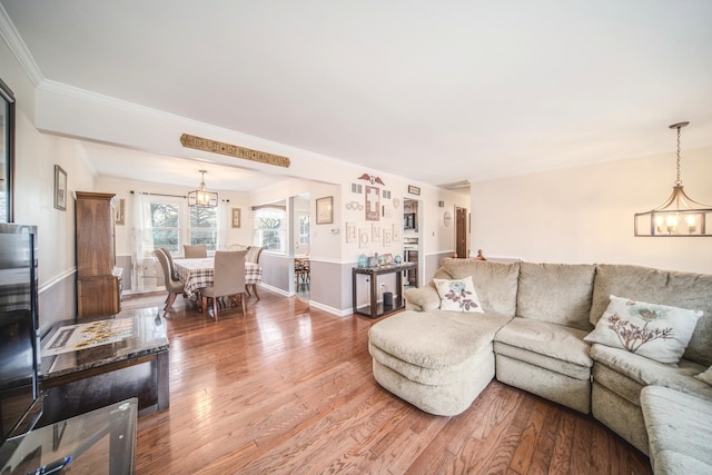 living area featuring an inviting chandelier, crown molding, and wood finished floors