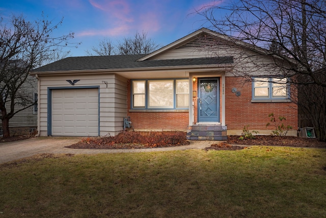 view of front of property featuring brick siding, entry steps, a garage, driveway, and a front lawn