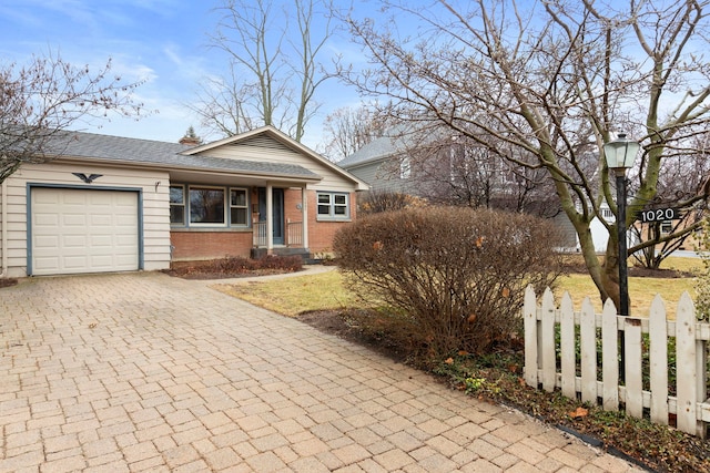 view of front facade with a fenced front yard, a garage, brick siding, a shingled roof, and decorative driveway