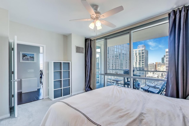 bedroom featuring light carpet, visible vents, baseboards, a view of city, and floor to ceiling windows