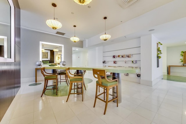 kitchen featuring baseboards, visible vents, hanging light fixtures, a kitchen bar, and open shelves