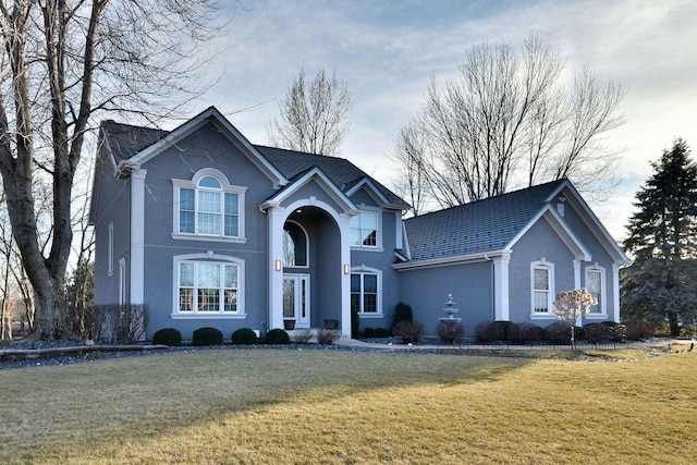 traditional-style house with a front lawn and stucco siding