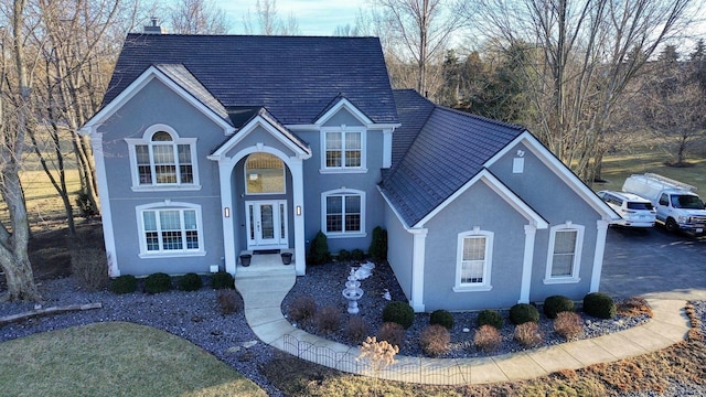 traditional-style home with a chimney and stucco siding