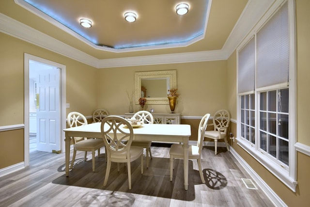 dining area featuring a raised ceiling, visible vents, crown molding, and wood finished floors