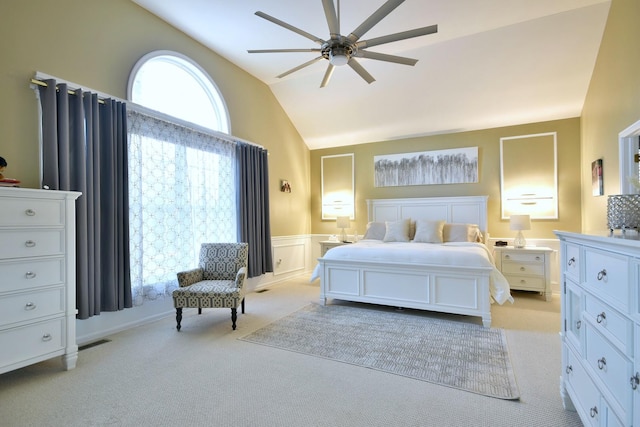 bedroom with light carpet, visible vents, wainscoting, vaulted ceiling, and a decorative wall