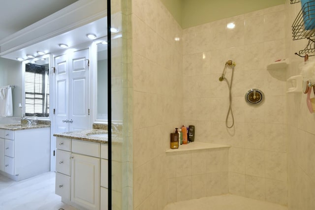 full bathroom with a sink, two vanities, and a tile shower