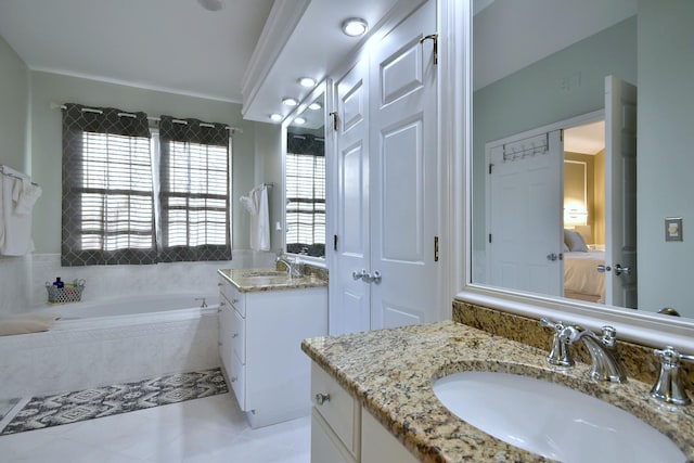 full bath featuring two vanities, a sink, ensuite bath, and a bath