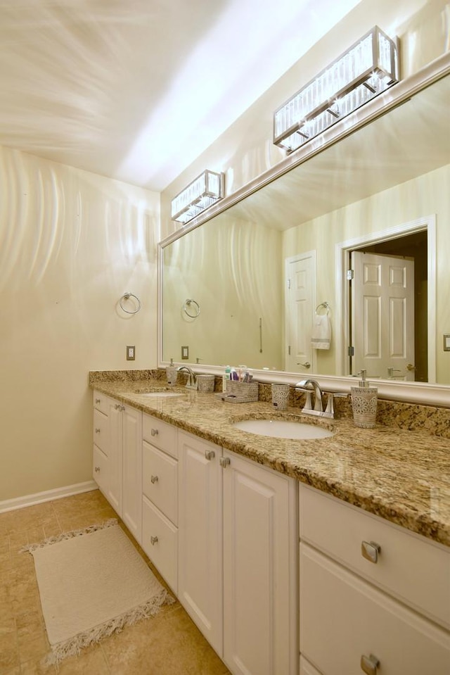 bathroom featuring double vanity, tile patterned flooring, a sink, and baseboards