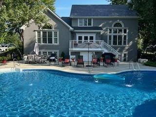 back of property with stairway, an outdoor pool, and a patio